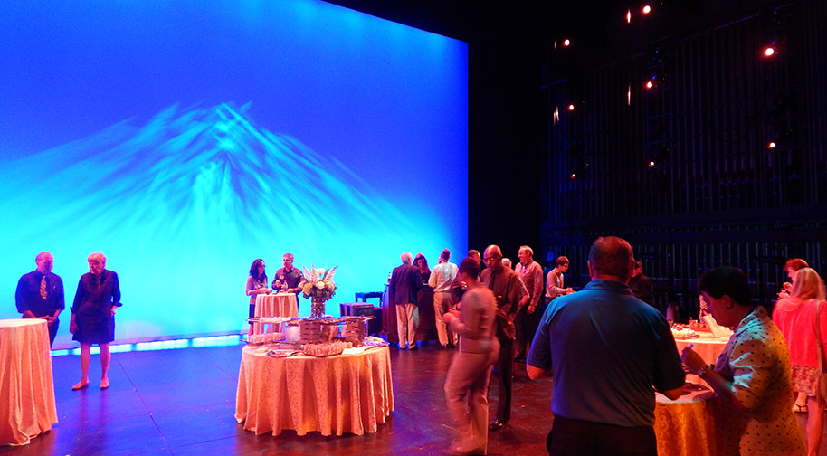 A social event with cocktail tables on the brightly lit Tarkington stage.