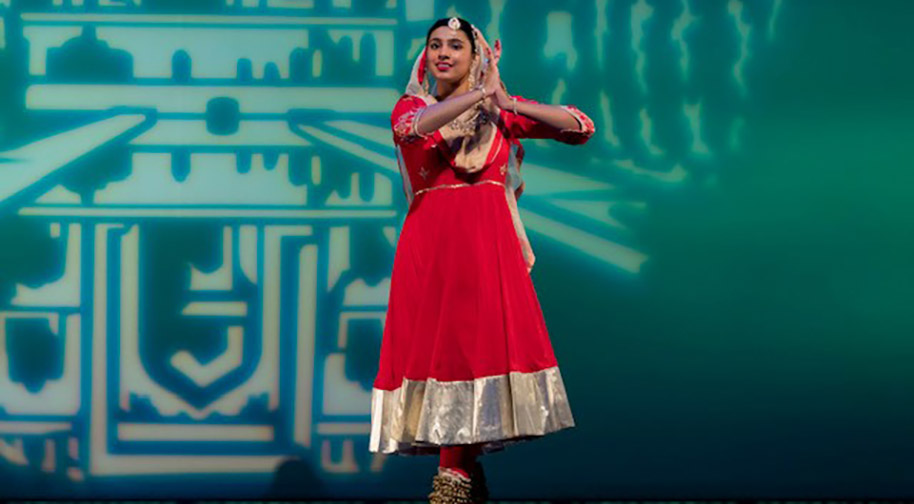 A dancer in a red and gold costume performs on the Tarkington stage.