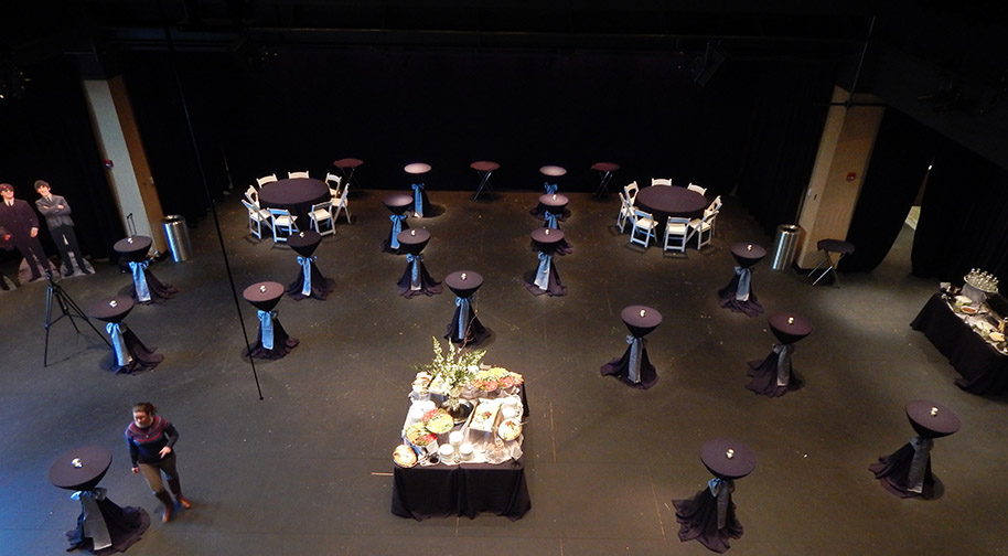 A corporate event in the Studio Theater from which seating has been removed. Cocktail tables and a buffet are in sleek black.