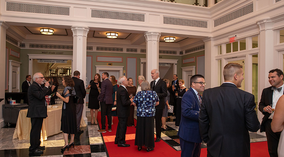 People mingle in the Palladium's West Lobby prior to an event. A red carpet leads from the entrance to an elevator.