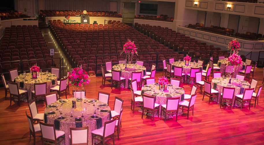 The Palladium stage set up with dining tables and pink lighting for a birthday party.