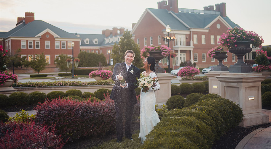 Following a wedding ceremony at the Palladium, the bridge and groom pop a champagne bottle in the West garden.