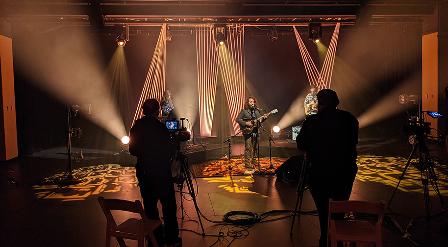 During a livestreamed concert in the Studio Theater green lasers shine behind a rock band.