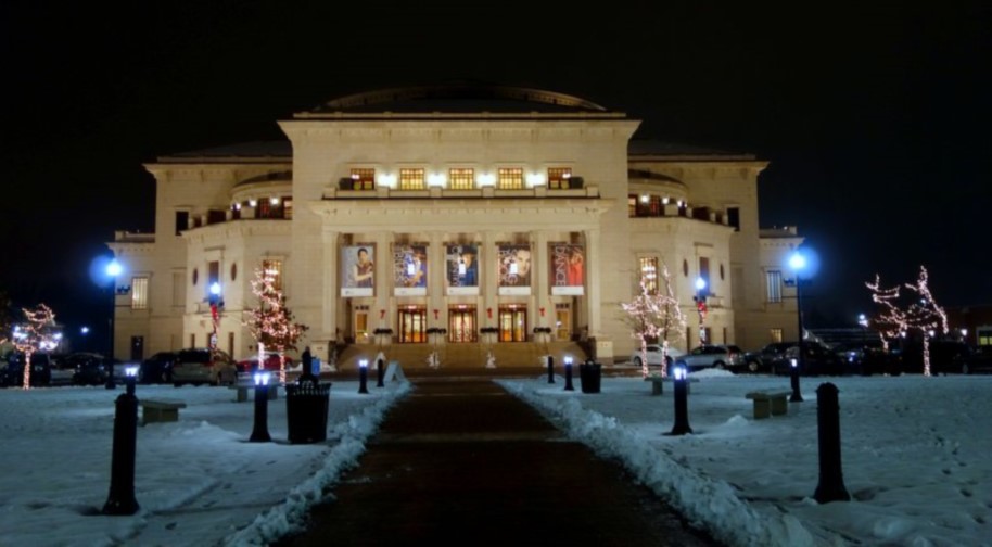 A large neoclassical limestone building, the Palladium, viewed from the south at night amid snow and Christmas lights.