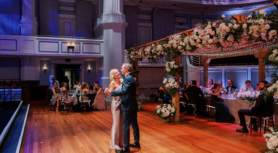 A bride and groom take their first dance at a wedding on the Palladium stage.