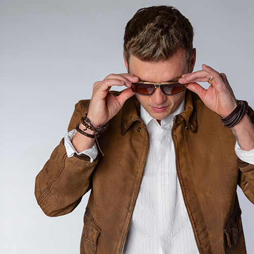 Pop star Nick Cannon poses in sunglasses and a brown suede jacket.