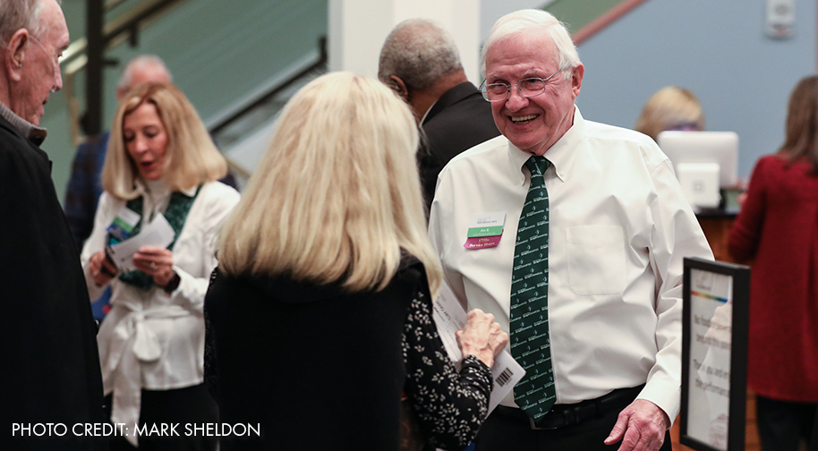 Two volunteers in white uniforms, a man and a woman, chat with patrons in the Palladium's Web Lobby.