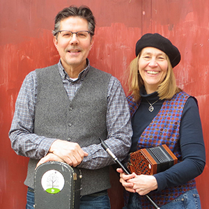 Man holds guitar case, woman holds concertina