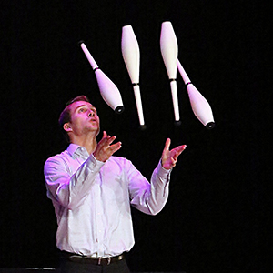 Man in white shirt juggle four bowling pins