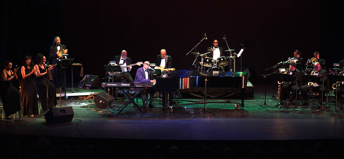 A jazz orchestra with three backing singers fills a stage