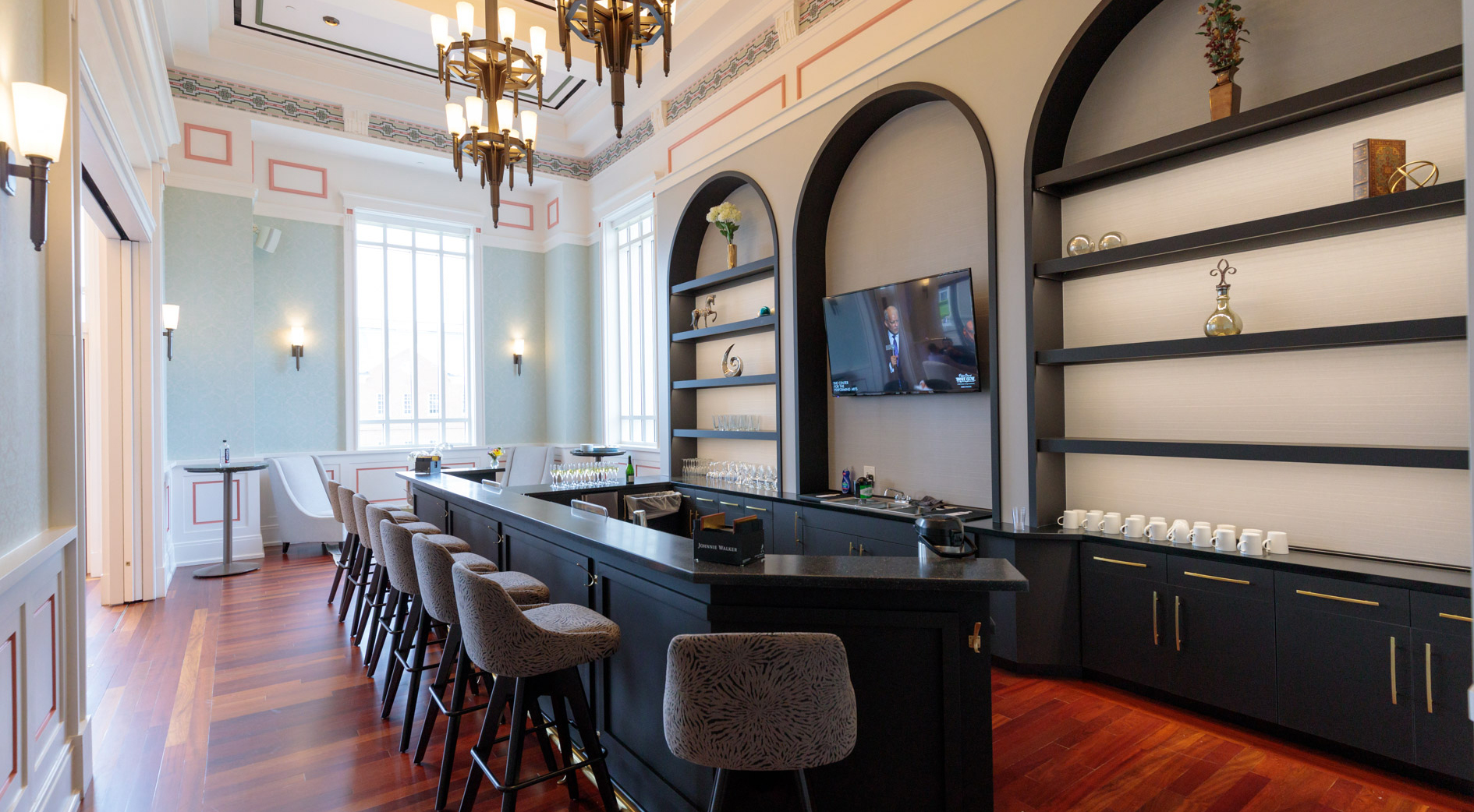 An elegant bar with stools, chandeliers and polished hardwood flooring