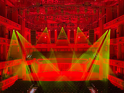 The Palladium concert hall is lit in deep red with yellow spotlights on the stage.