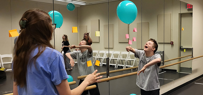 Prism Project performers take a break to play with baloons in a dance studio.