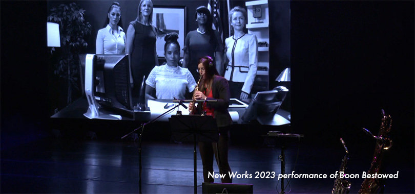 A saxophonist plays against a video playing images of women at work. New Works 2023 performance of Boon Bestowed.