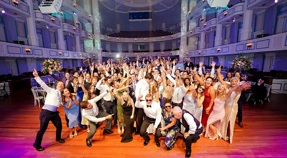 A wedding party takes a group photo on the stage of the Palladium.