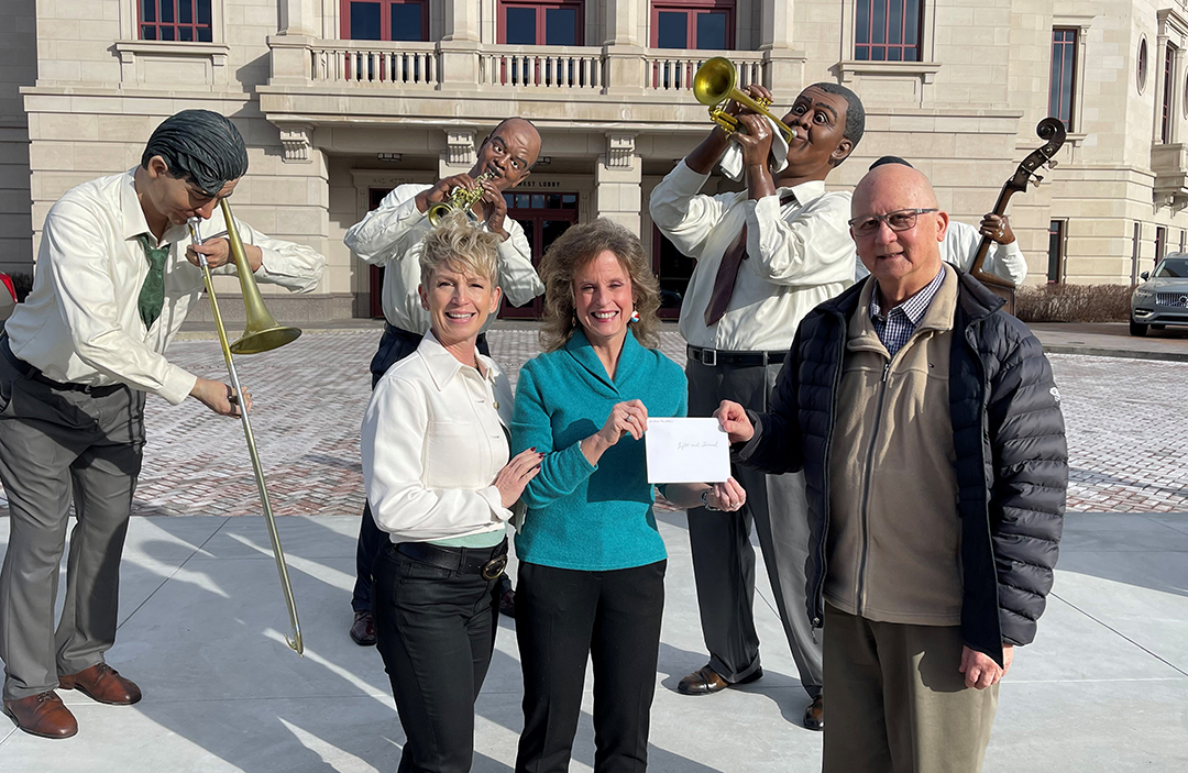 A man passes a check to two women as they stand outside the Palladium concert hall.