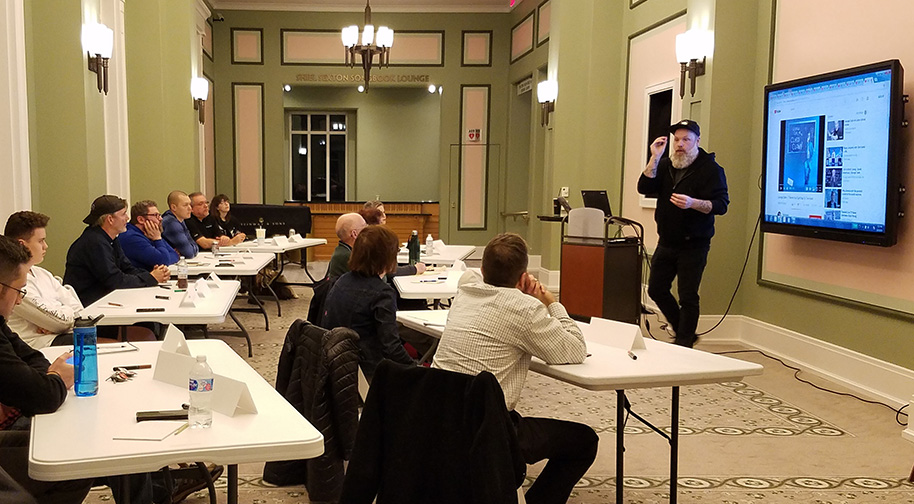 Professional comic Mat Alano-Martin leads an Intro to Stand-Up Comedy class, showing clips of stand-up comics over history.